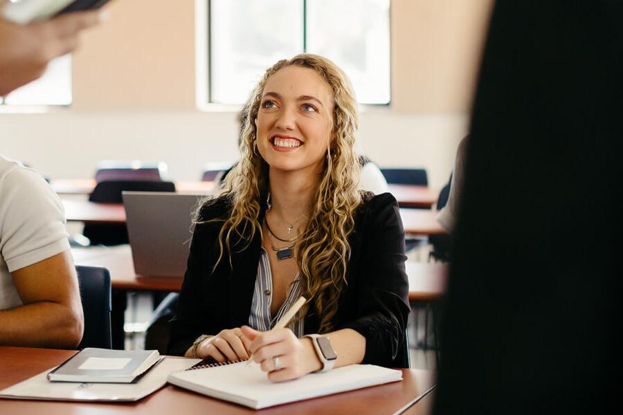 Creative writing student writes in a notebook in a classroom.